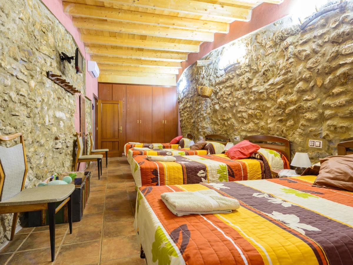 Habitación con 3 camas individuales y pared de piedra