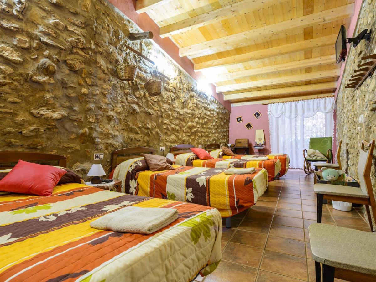 Habitación con 4 camas individuales y pared de piedra